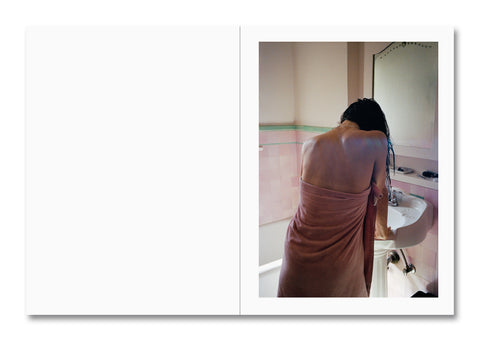 Woman in a pink towel standing in a bathroom.