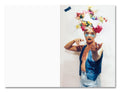 Person with colorful floral headpiece and denim outfit against a white background